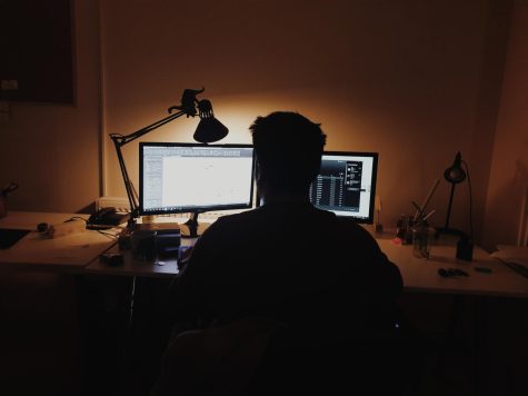 A person sitting in front of two computer monitors. Photo courtesy Oğuzhan Akdoğan via Unsplash 