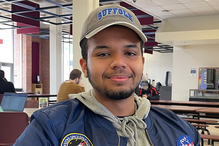 Ephrem+Romao%2C+19%2C+a+liberal+arts+major+from+Shirley+who+is+graduating%2C+talks+about+his+experience+at+Suffolk+while+relaxing+in+the+Babylon+Student+Center+cafeteria+on+March+15%2C+2023.+%28Compass+News%2FJames+Quigley%29