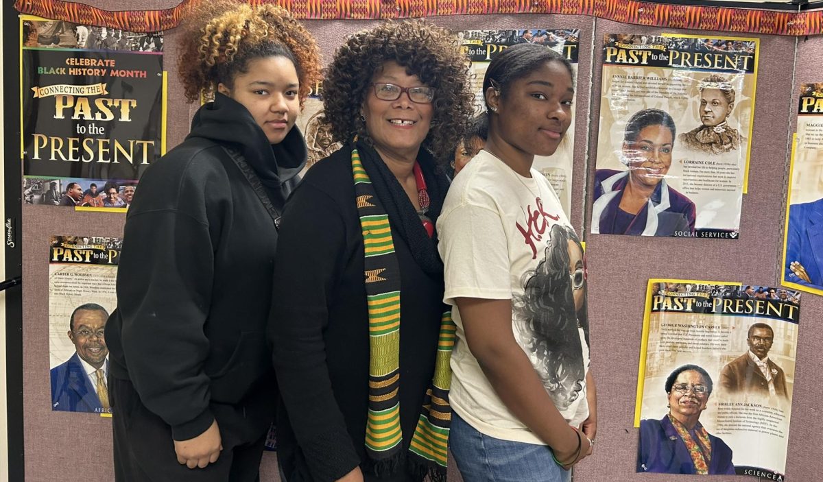  Carol A Gordon, founder of Unspoken History Treasures poses with her two granddaughters in front of a poster of African-American heroes on Wednesday, Feb. 21, 2024. (Compass News/ Giselle Castro) 