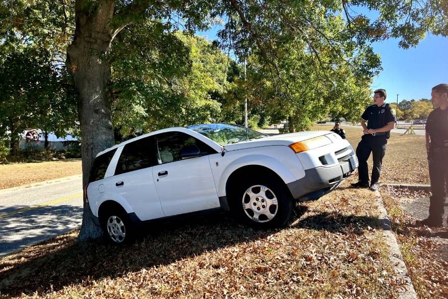 Tuesday, Oct. 8, around 10:55 a.m. public safety inspects a car that rolled into a tree in parking lot 4. (Compass News/Jay Kass)